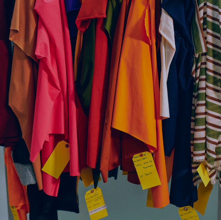 Colorful fabric swatches and textile samples with tags hanging on a rail, showcasing material selection for fashion design, apparel production, or textile inventory.