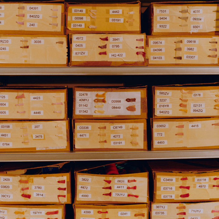 Archive boxes with colored thread samples labeled with reference numbers.