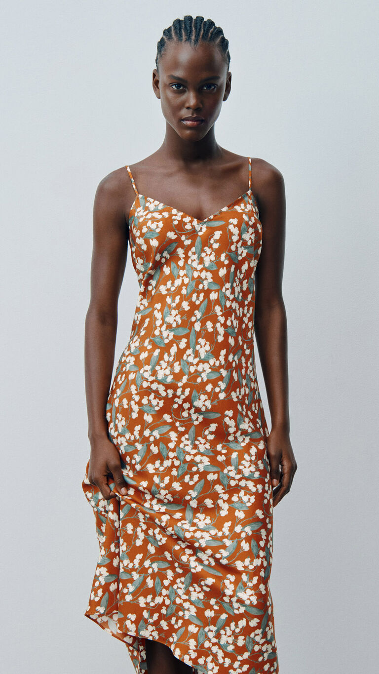 Mannequin portant une robe nuisette &agrave; fines bretelles &agrave; imprim&eacute; floral orange et blanc, sur fond gris clair.