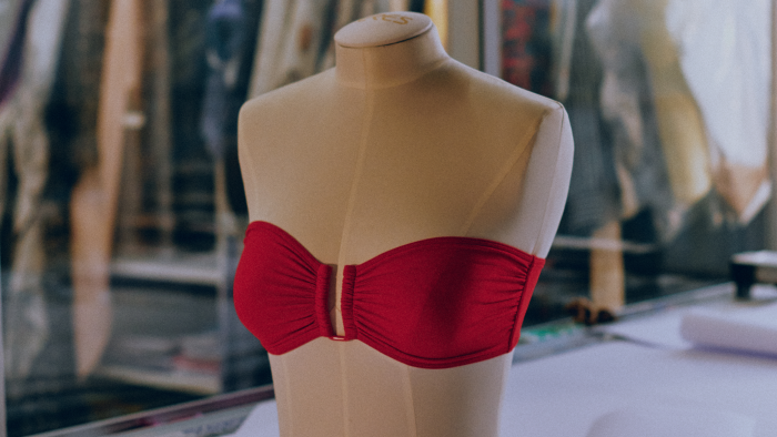Mannequin torso displaying a red strapless top in a fashion design studio or atelier, highlighting garment creation and apparel display.