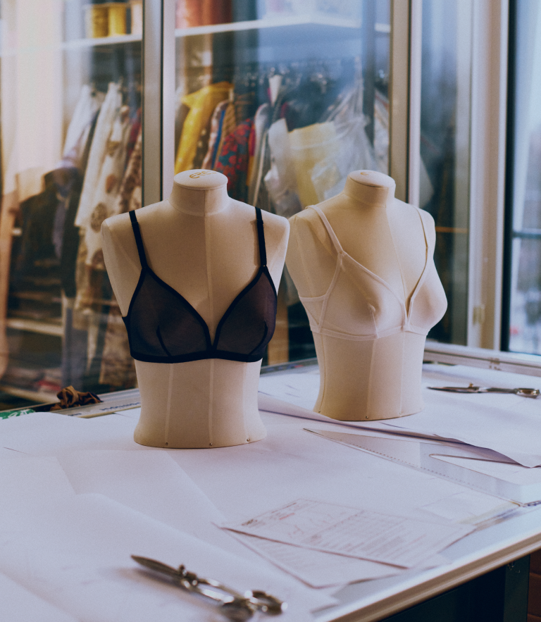 Black and white lingerie bras displayed on mannequins on a design table in a fashion studio, highlighting garment creation and the design process.