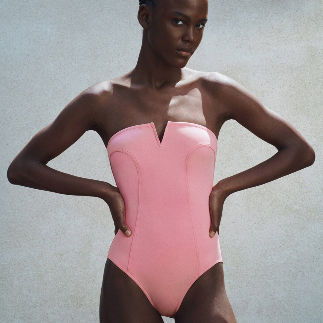 Woman in strapless pink swimsuit with V-neck.