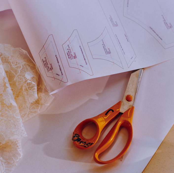 Sewing pattern on a table with scissors and lace fabric.